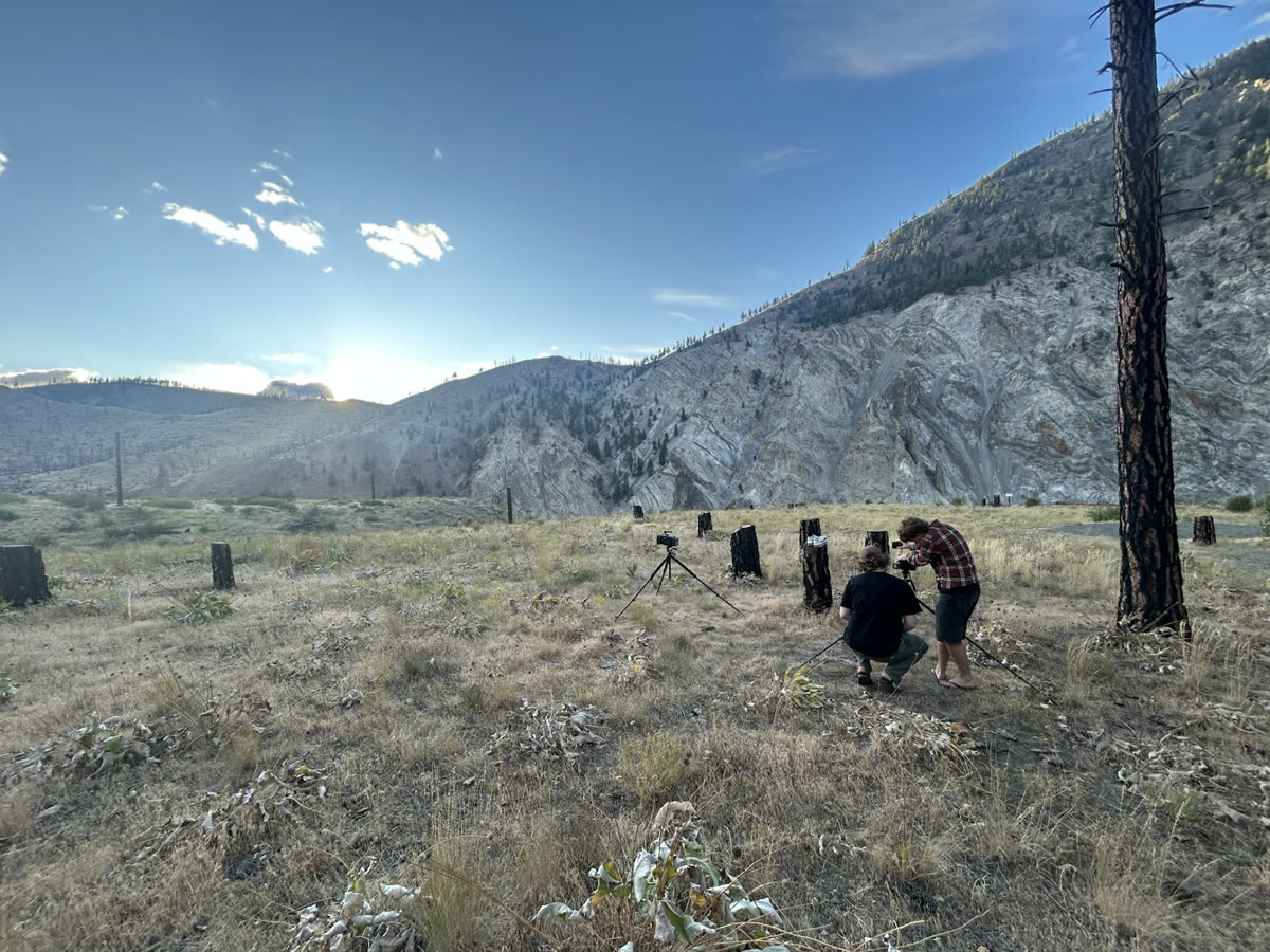 Film crew setting up cameras at sunset in a mountain valley